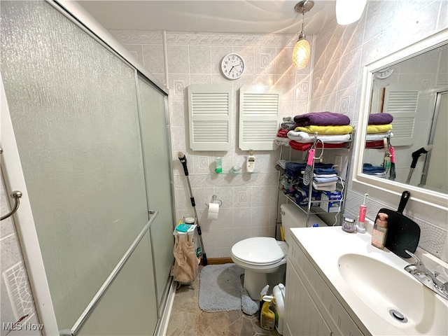 full bathroom with a stall shower, tile walls, toilet, and vanity