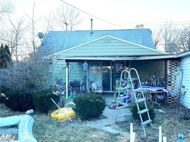 rear view of property featuring roof with shingles and a patio