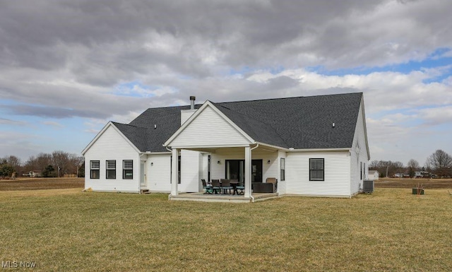 rear view of property with a patio, a yard, and a shingled roof