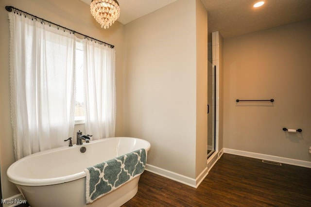 bathroom featuring baseboards, a soaking tub, a healthy amount of sunlight, and wood finished floors