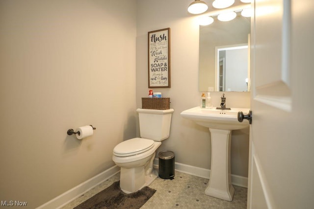 half bathroom featuring baseboards and toilet