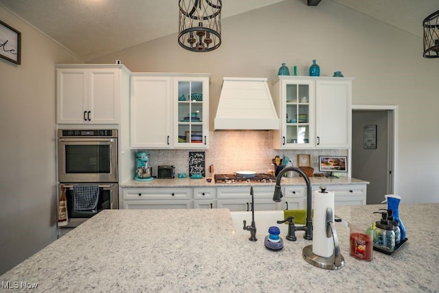 kitchen featuring custom exhaust hood, backsplash, appliances with stainless steel finishes, and vaulted ceiling