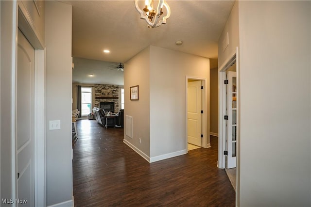 hall featuring a chandelier, baseboards, visible vents, and wood finished floors