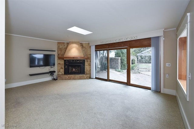 unfurnished living room with a skylight, a fireplace, carpet flooring, and baseboards