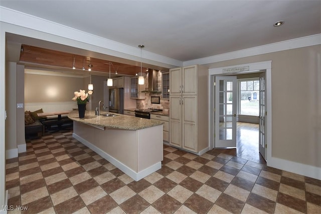 kitchen featuring cream cabinets, a sink, wall chimney range hood, freestanding refrigerator, and black range