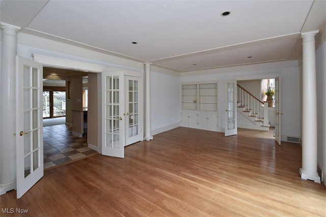 unfurnished room featuring ornate columns, light wood-style flooring, visible vents, and french doors