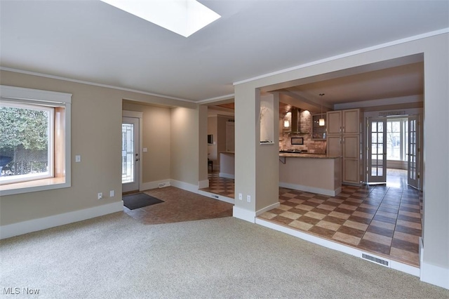 entrance foyer with light carpet, a skylight, visible vents, baseboards, and ornamental molding