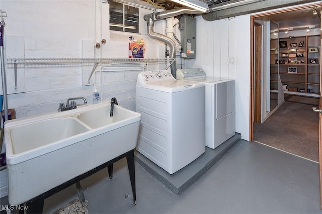 washroom featuring concrete block wall, laundry area, electric panel, washer and clothes dryer, and a sink