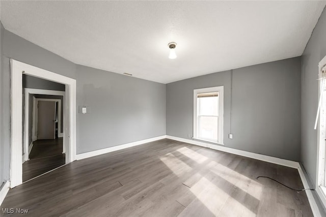 unfurnished room featuring dark wood-style floors and baseboards