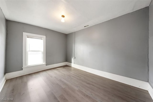 unfurnished room featuring visible vents, baseboards, and wood finished floors