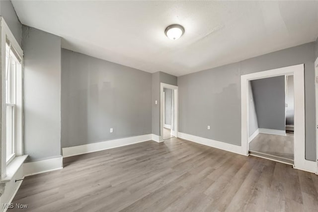 spare room with a healthy amount of sunlight, baseboards, and wood finished floors