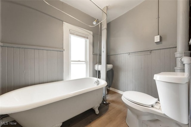 full bathroom featuring a wainscoted wall, a freestanding bath, toilet, and wood finished floors