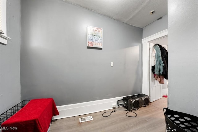 mudroom with a textured ceiling, visible vents, and wood finished floors