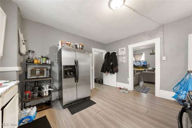 kitchen with stainless steel appliances, light wood-style flooring, and baseboards