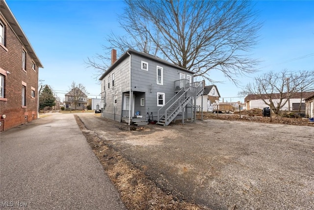 back of property with aphalt driveway, a residential view, and a chimney