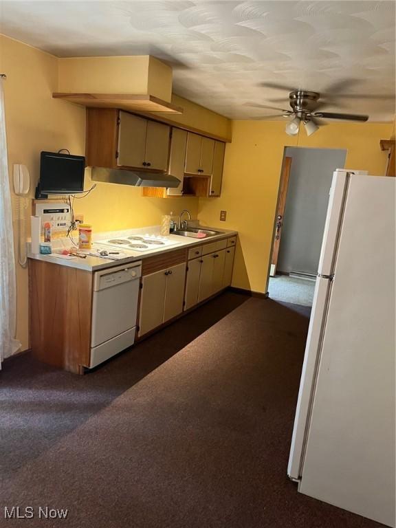 kitchen featuring light countertops, dark carpet, a sink, white appliances, and under cabinet range hood