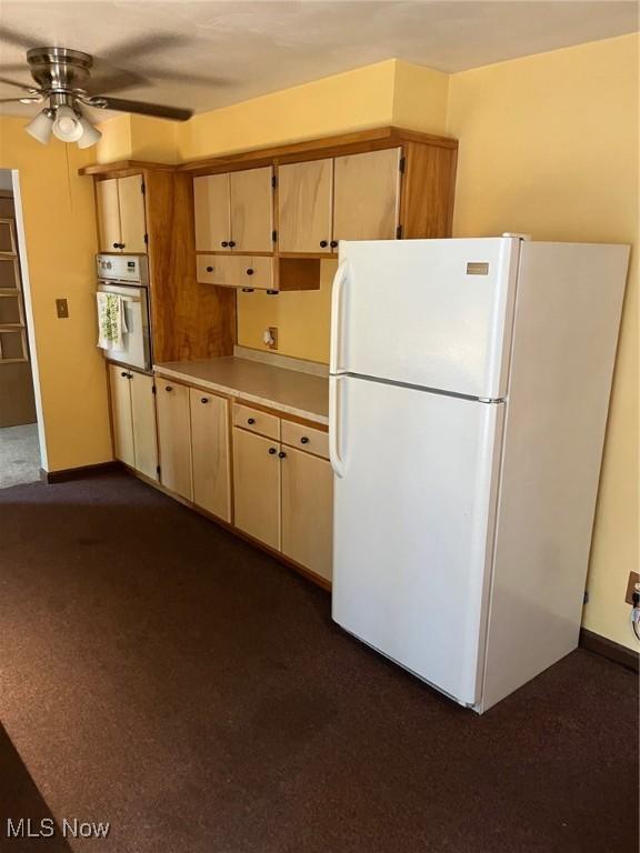 kitchen featuring white appliances, ceiling fan, baseboards, and light countertops