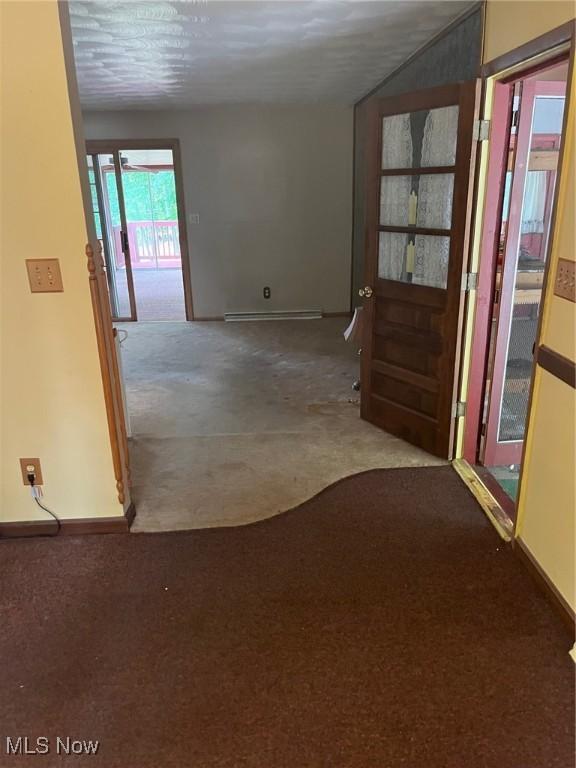 hallway with carpet, baseboards, and baseboard heating