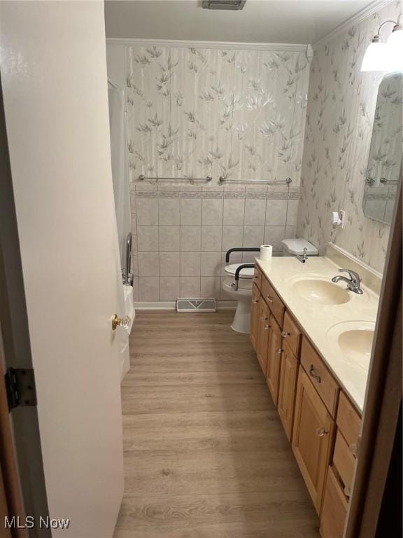 full bathroom featuring wallpapered walls, visible vents, toilet, wood finished floors, and a sink