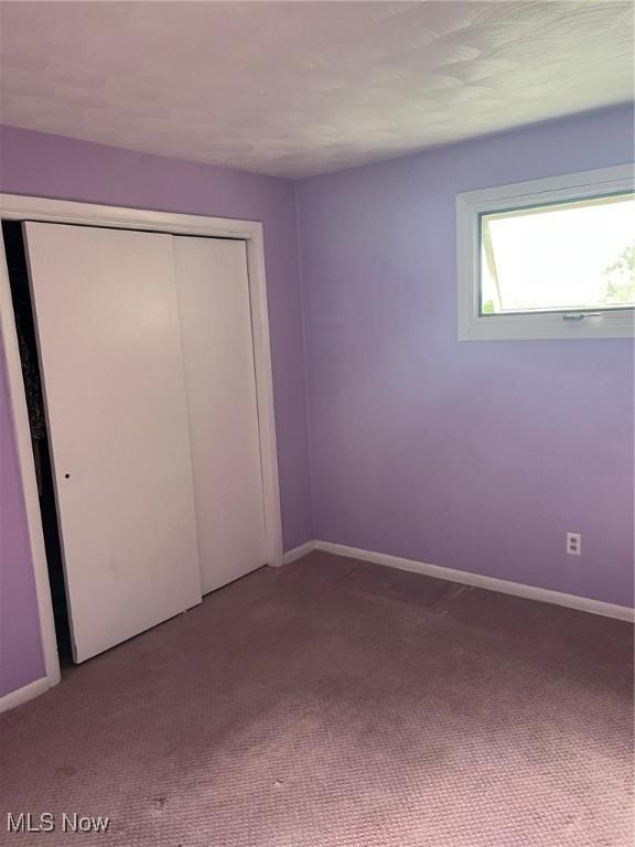 unfurnished bedroom with a closet, carpet flooring, and baseboards