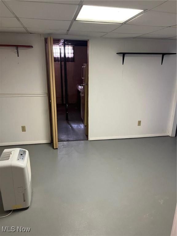 basement with baseboards and a drop ceiling