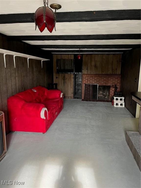 living area with wooden walls, finished concrete floors, a fireplace, and beamed ceiling