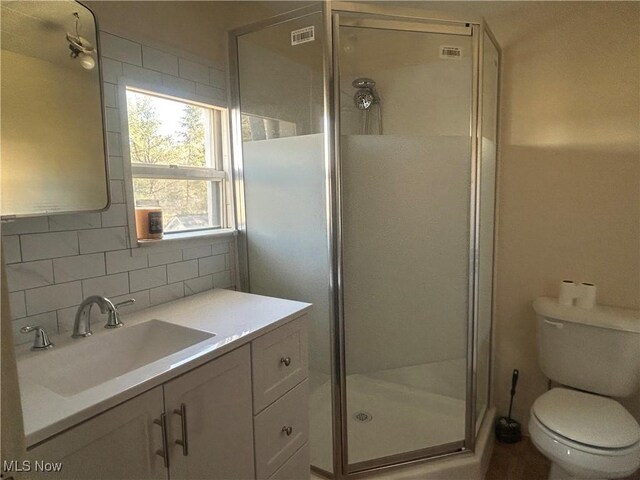 full bathroom featuring toilet, a stall shower, backsplash, and vanity