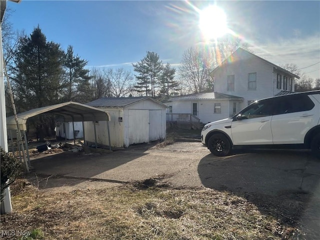 view of side of home featuring a detached carport, metal roof, an outbuilding, and a storage unit