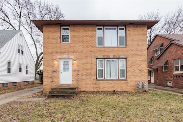 view of front of house featuring entry steps, brick siding, and a front yard