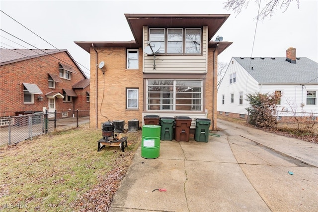 back of property featuring central air condition unit, a yard, fence, and brick siding