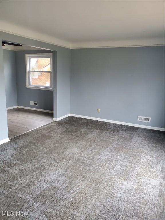 unfurnished room with ornamental molding, carpet, visible vents, and baseboards