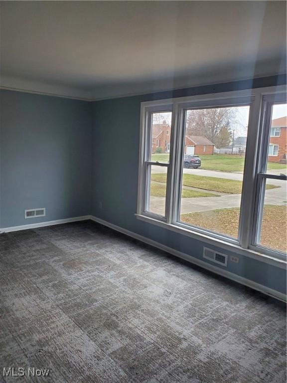 spare room featuring carpet flooring, crown molding, visible vents, and baseboards