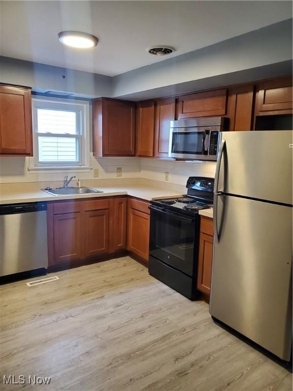 kitchen with stainless steel appliances, visible vents, a sink, and light wood finished floors