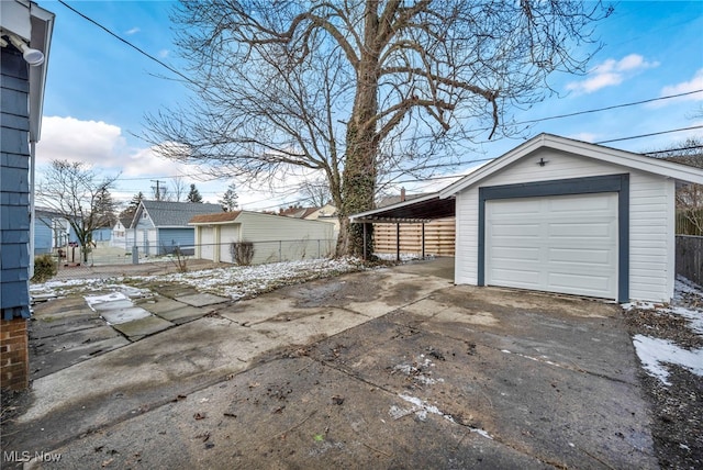 detached garage featuring fence and concrete driveway