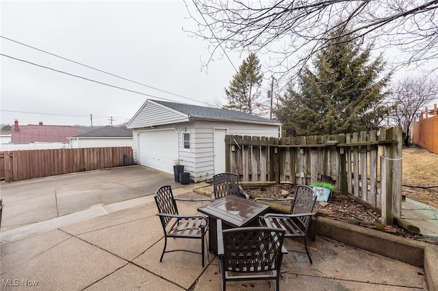 view of patio / terrace with an outbuilding, a fenced backyard, and a detached garage