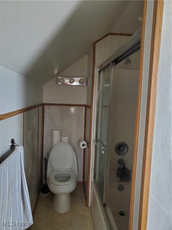 bathroom with toilet, tile patterned flooring, vaulted ceiling, and combined bath / shower with glass door