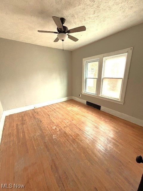 spare room with visible vents, light wood-style flooring, baseboards, and a textured ceiling