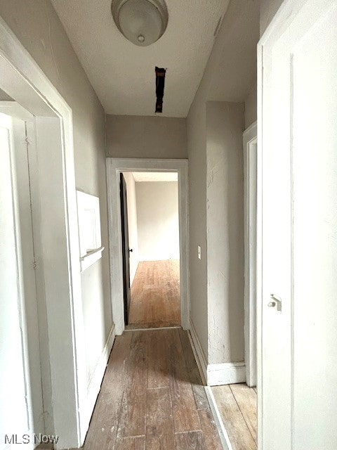 corridor featuring baseboards and hardwood / wood-style flooring