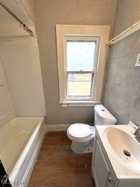 bathroom with a textured wall, toilet, and wood finished floors