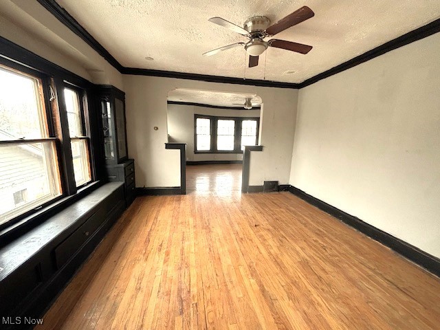 empty room featuring ornamental molding, a textured ceiling, and wood finished floors