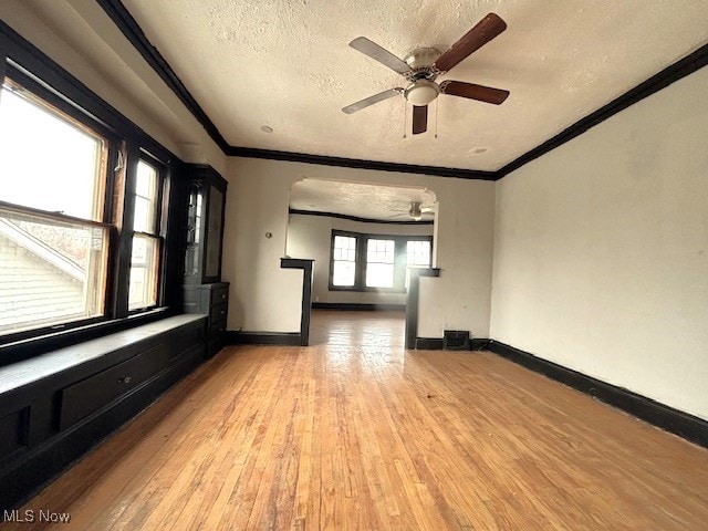 spare room featuring light wood-style flooring, ornamental molding, and a textured ceiling