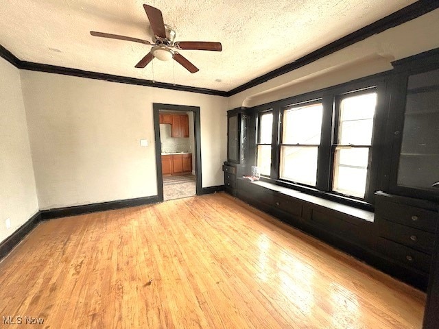 unfurnished bedroom with ornamental molding, light wood-type flooring, a textured ceiling, and baseboards