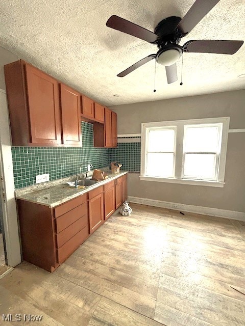 kitchen featuring tasteful backsplash, light countertops, a sink, and light wood finished floors