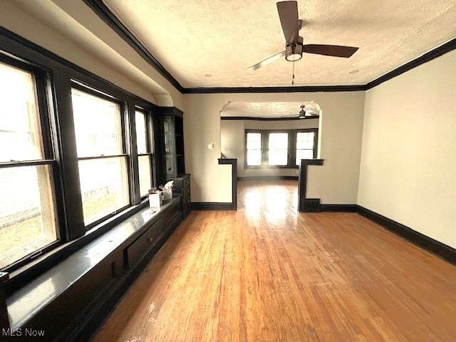 spare room featuring a textured ceiling, ornamental molding, wood finished floors, and baseboards