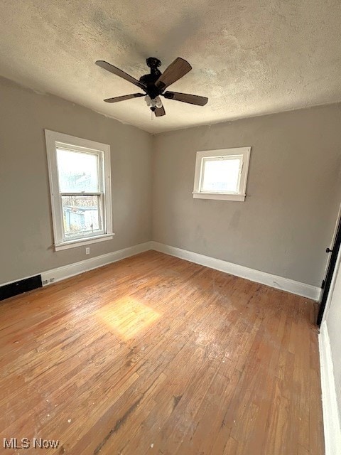 unfurnished room with baseboards, ceiling fan, a textured ceiling, and light wood-style floors