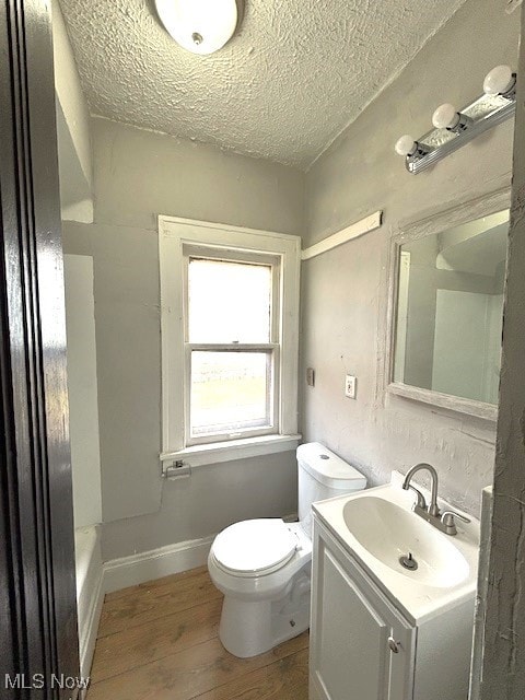 bathroom featuring toilet, vanity, a textured ceiling, wood finished floors, and baseboards