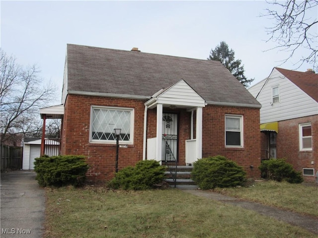 view of front of home featuring a shingled roof, a front lawn, and brick siding