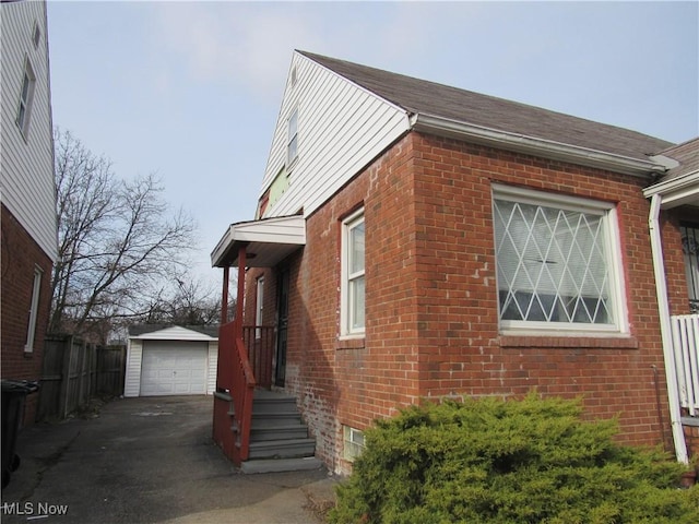 view of home's exterior with an outbuilding, driveway, brick siding, and a garage