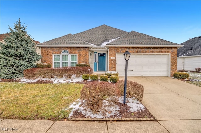 single story home with an attached garage, brick siding, concrete driveway, roof with shingles, and a front yard