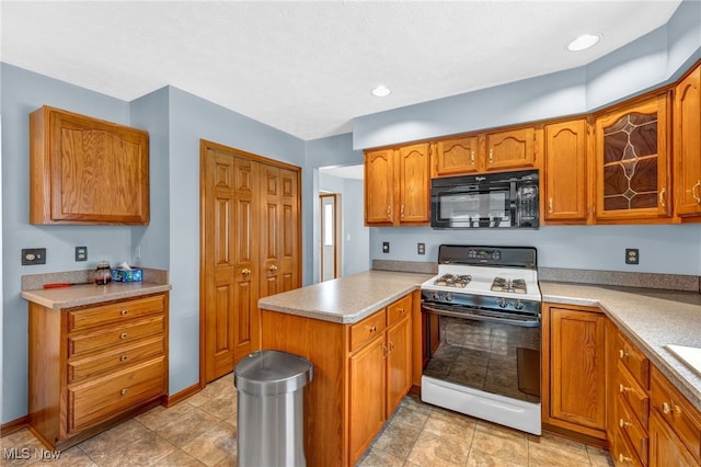 kitchen featuring gas range oven, light countertops, brown cabinetry, black microwave, and a peninsula